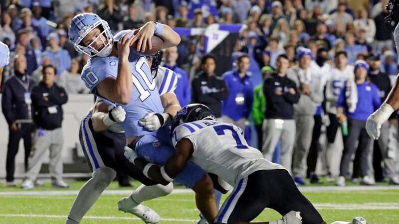 North Carolina quarterback Drake Maye (10) fights through a tackle attempt by Duke cornerback...