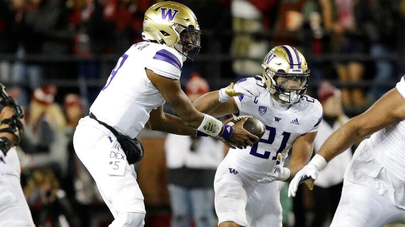 Washington quarterback Michael Penix Jr., left, hands the ball to running back Wayne Taulapapa...
